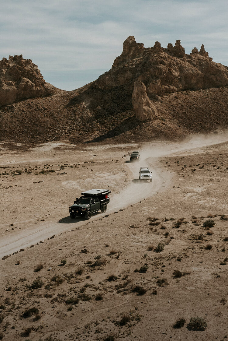 Desert landscape with rocky formations and a road with vehicles.