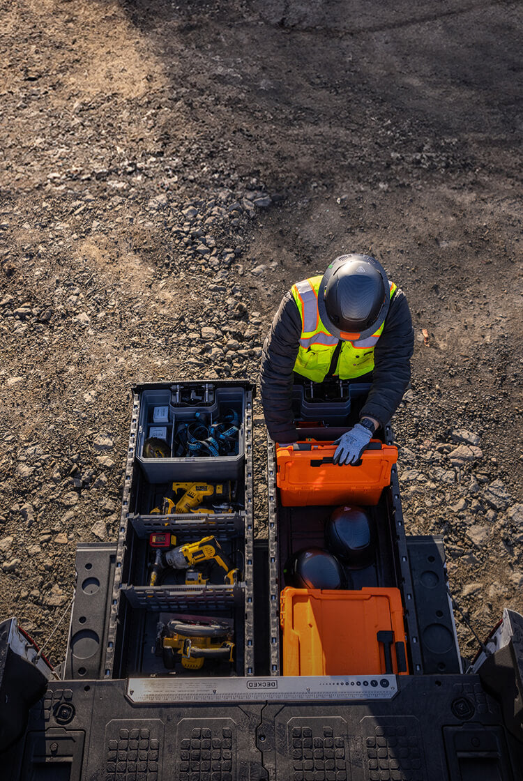 Person in high-visibility vest and helmet retrieving his tools from his Drawer System on a construction site