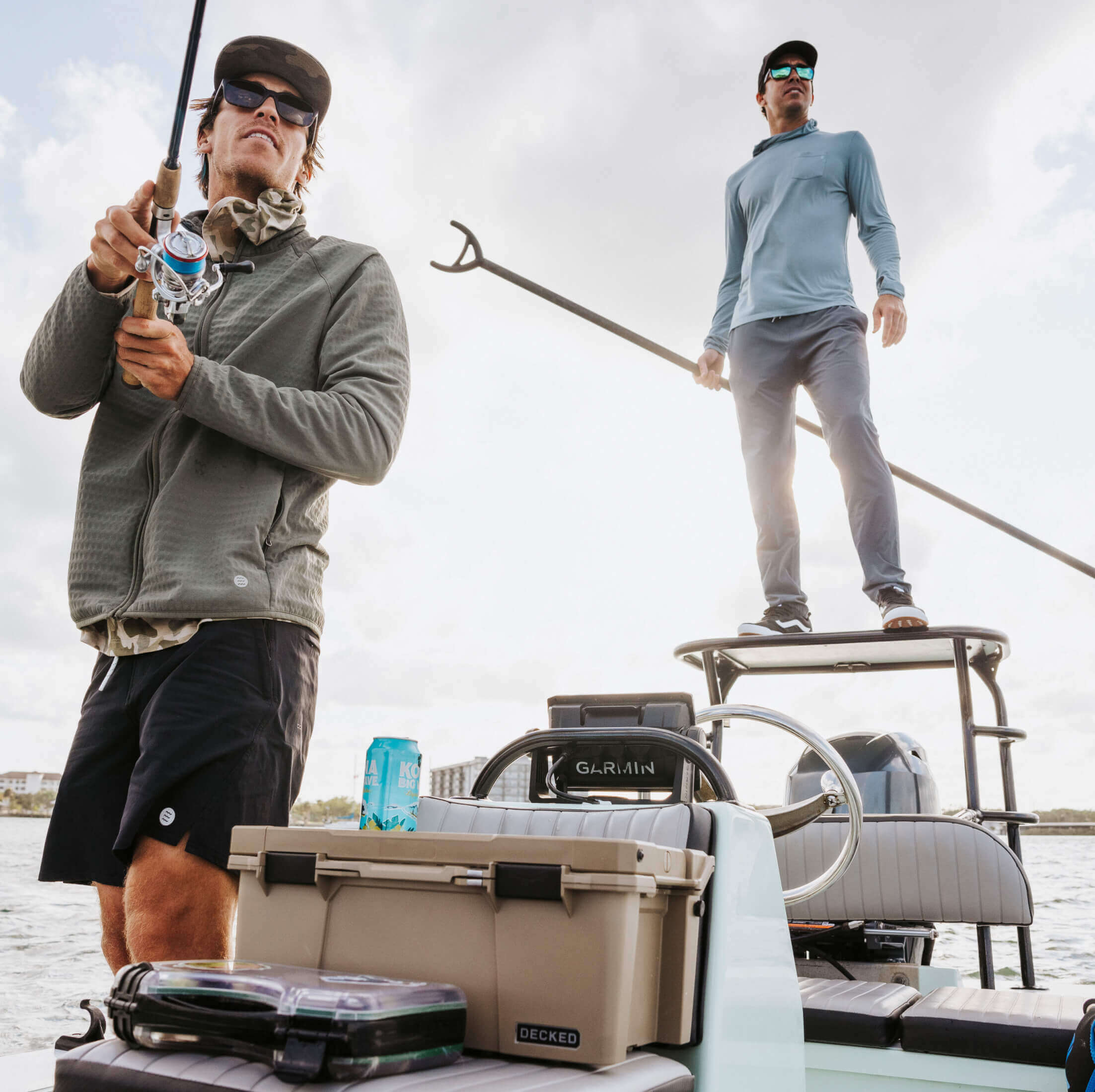 Two men on a boat with fishing gear and a cooler, enjoying a day of fishing.