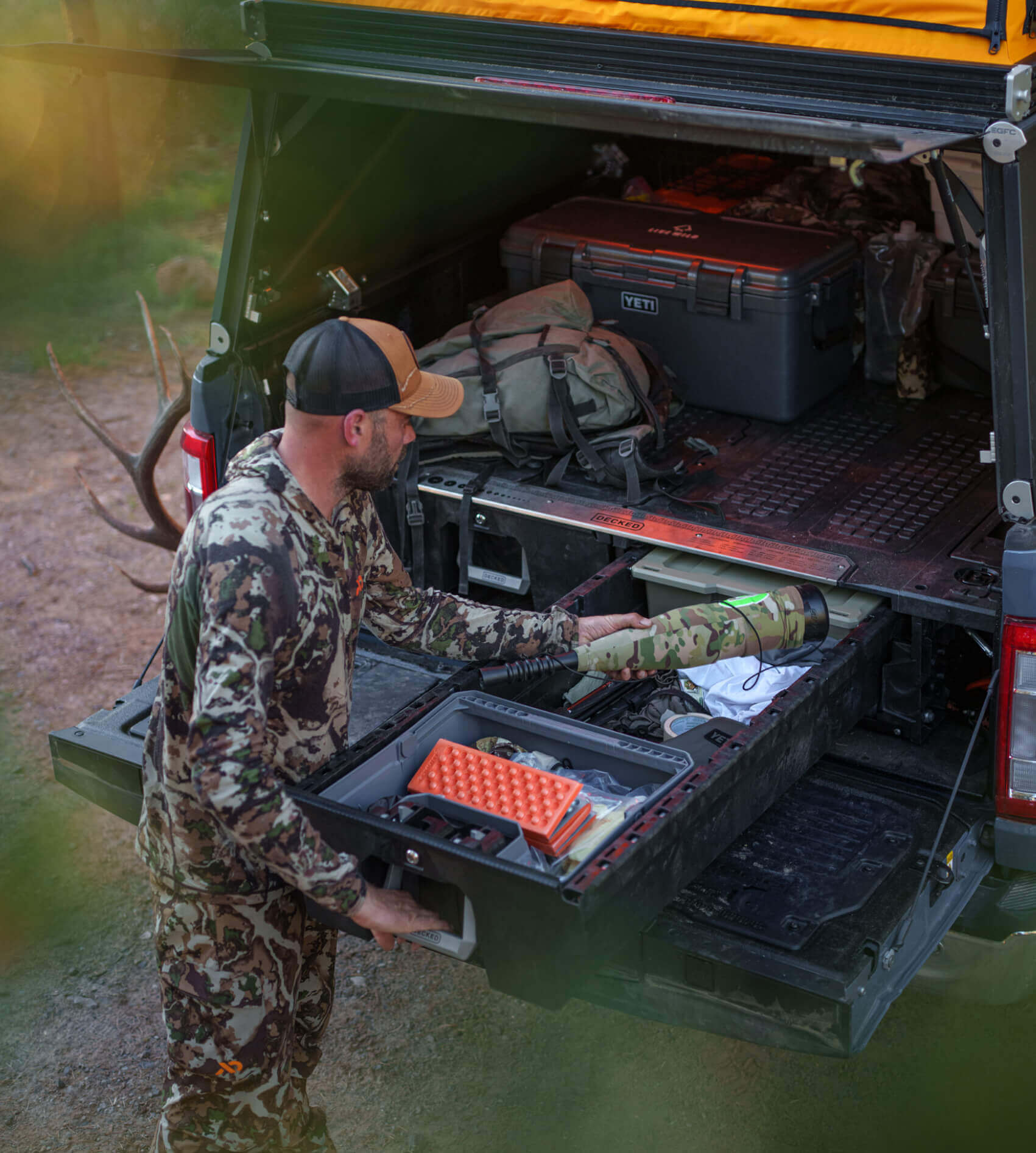 Remi Warren in camouflage gear preparing to head into the Elk woods, standing next to his Drawer System filled with hunting supplies.
