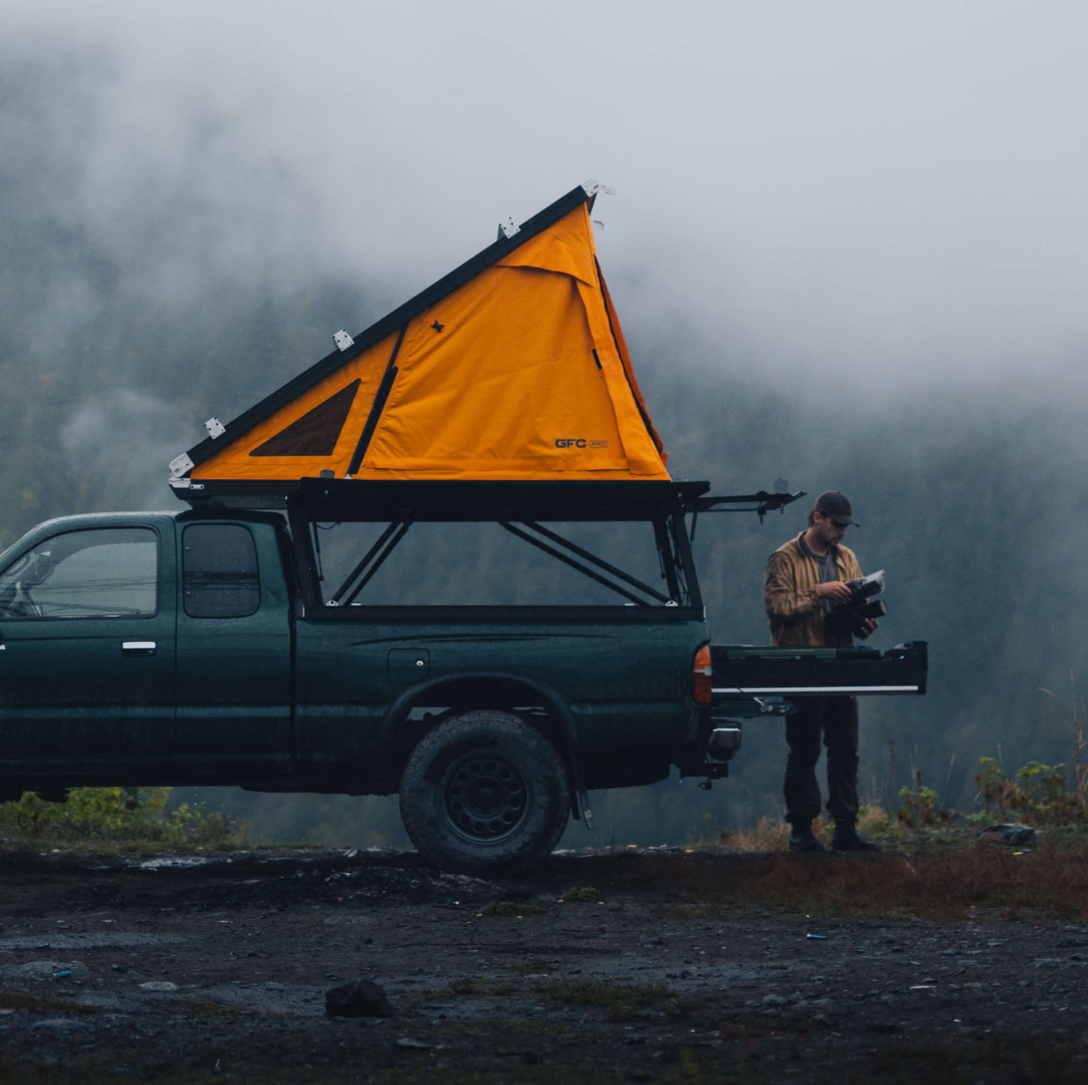 Person standing next to a truck with an orange rooftop tent and a DECKED Drawer System.