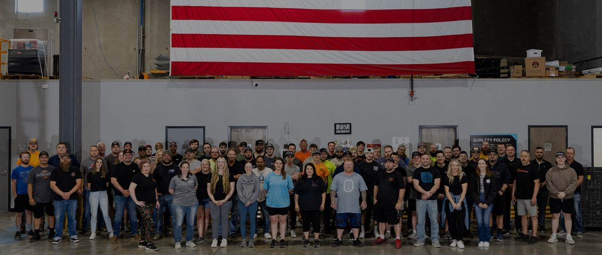 A group of factory workers at the DECKED factory underneath an American Flag.