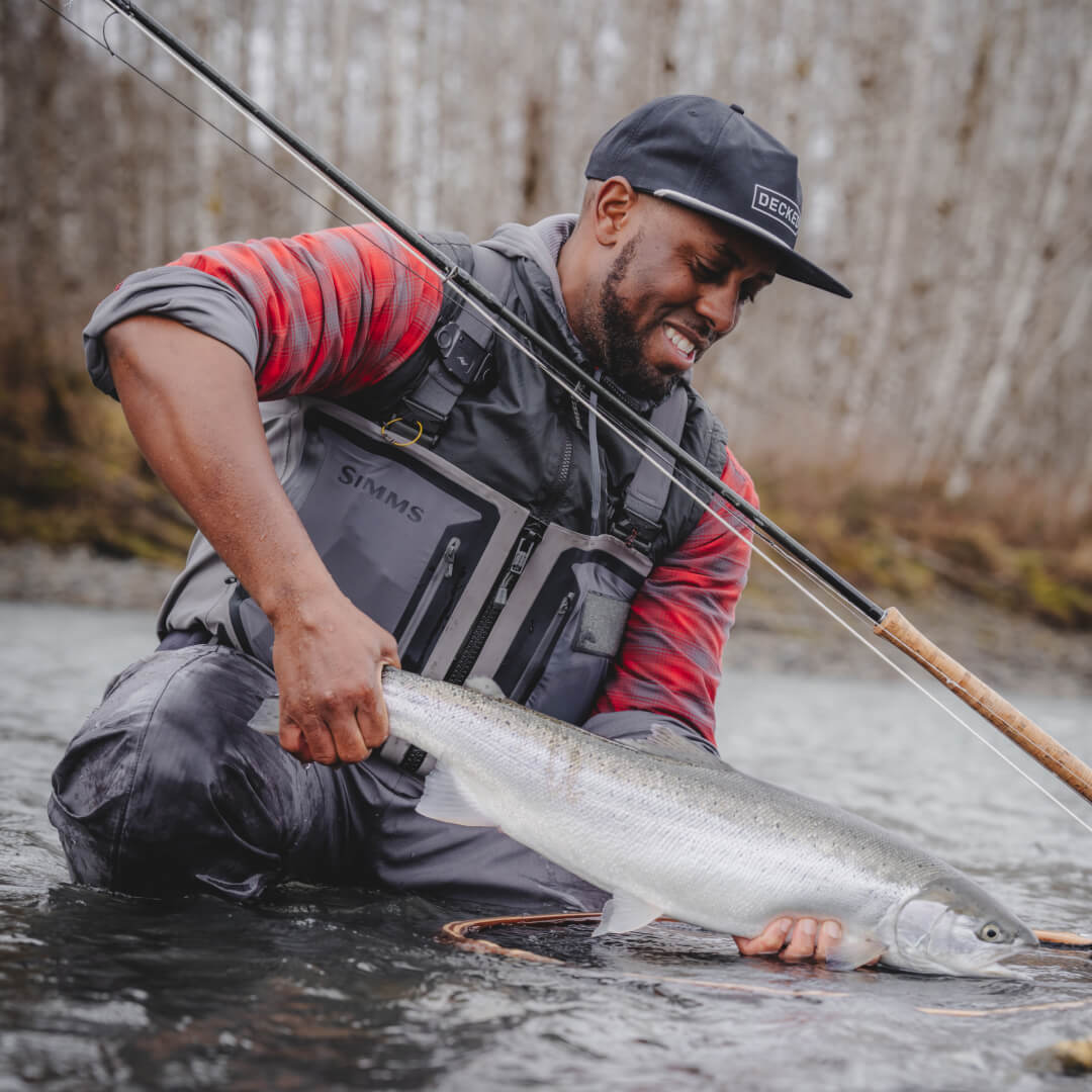 Lael Johnson in the river holding a beautiful fish he caught on the fly.