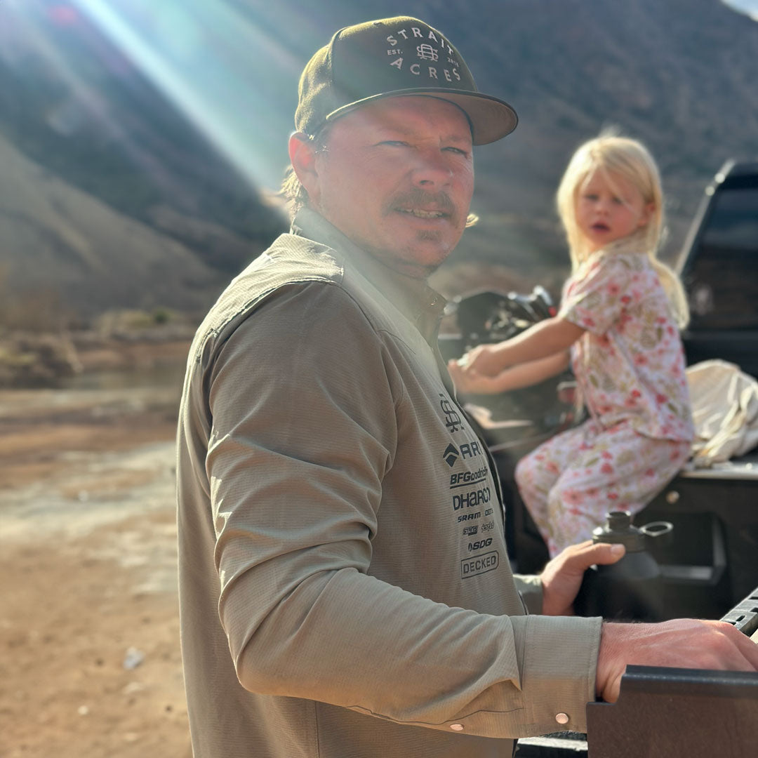 Kyle Strait smiling, standing next to his DECKED Drawer System with his daughter in the background.