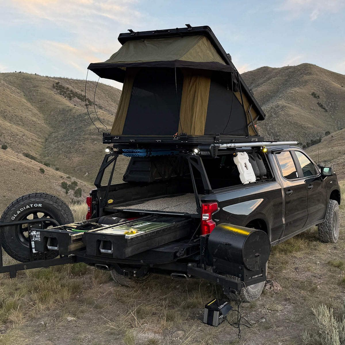 Black truck with a rooftop tent in a desert landscape