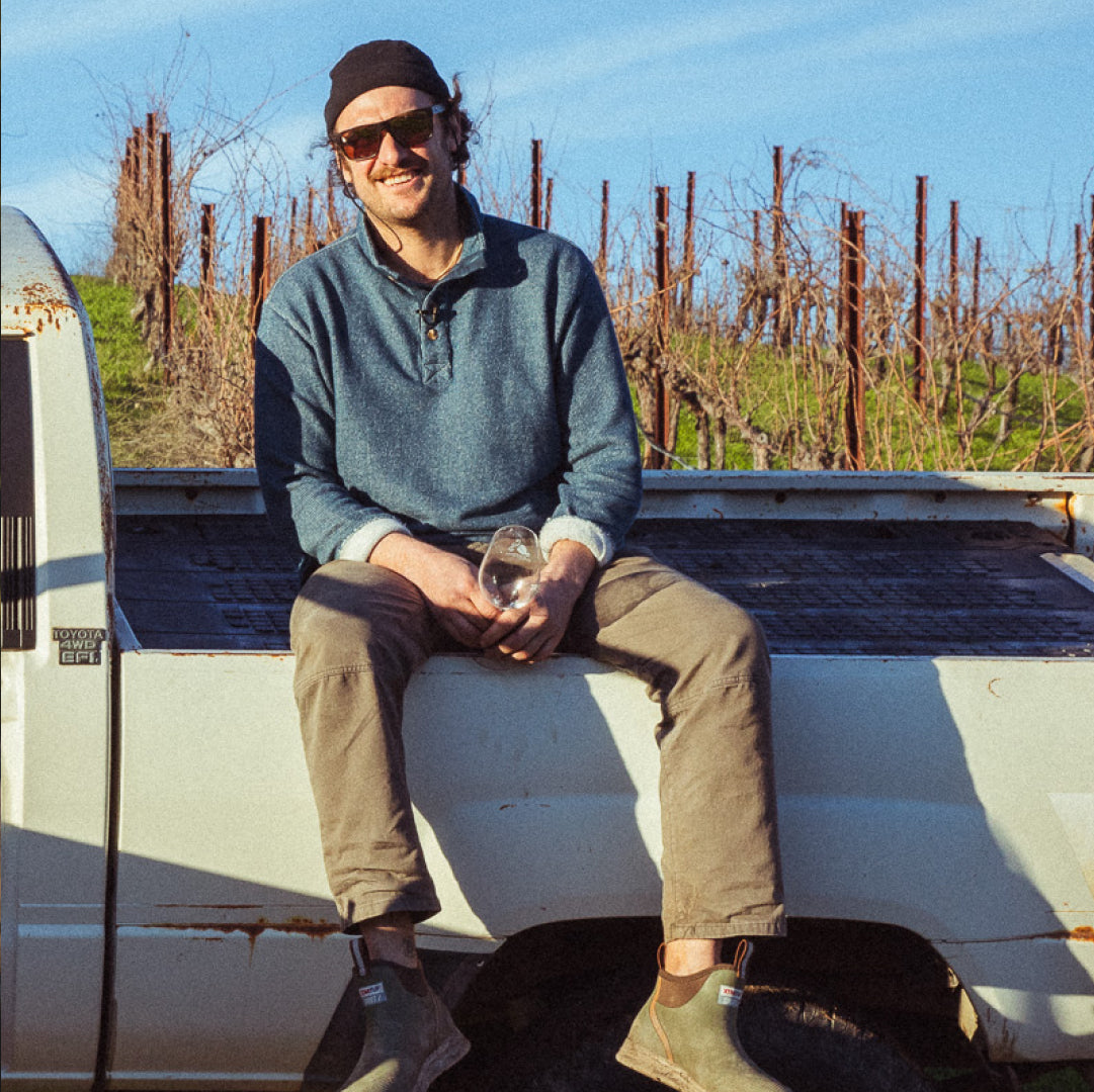 Brad Leone sitting on the edge of his truck bed in a vineyard.