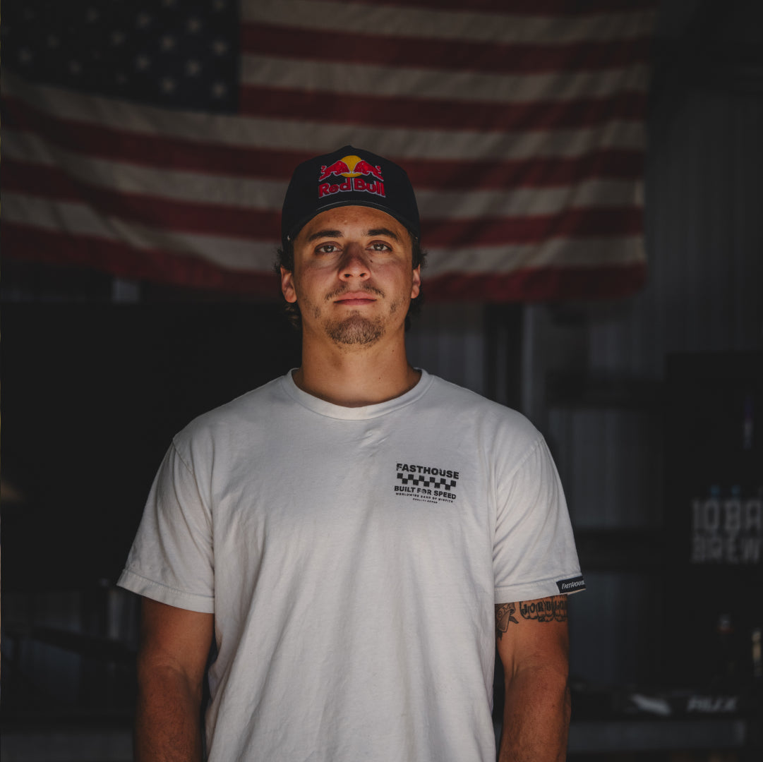 Carson Storch standing in his RedBull hat in front of an American Flag.