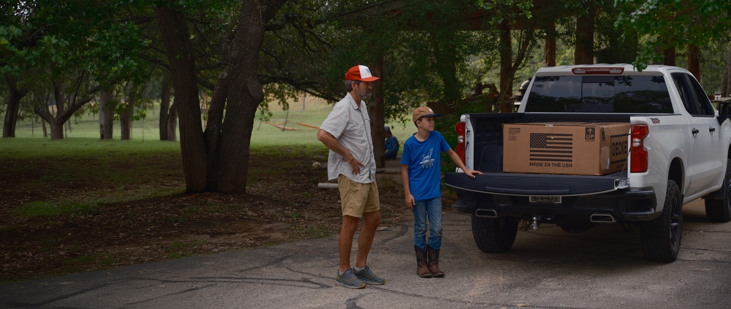 Dad and son standing beside a pickup truck with a boxed DECKED Drawer System in the truck bed before installation.