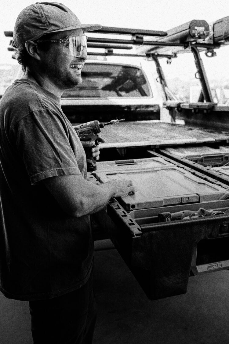 A black and white image of two contractors retrieving tools out of the Drawer System in their work truck.