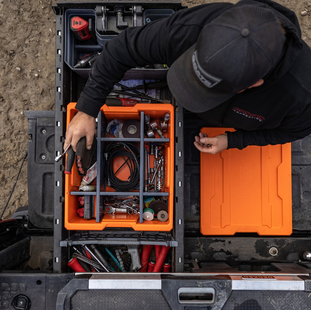 Overhead view of a worker organizing tools and accessories in a DECKED PayLoader using the customizable POD divider system.