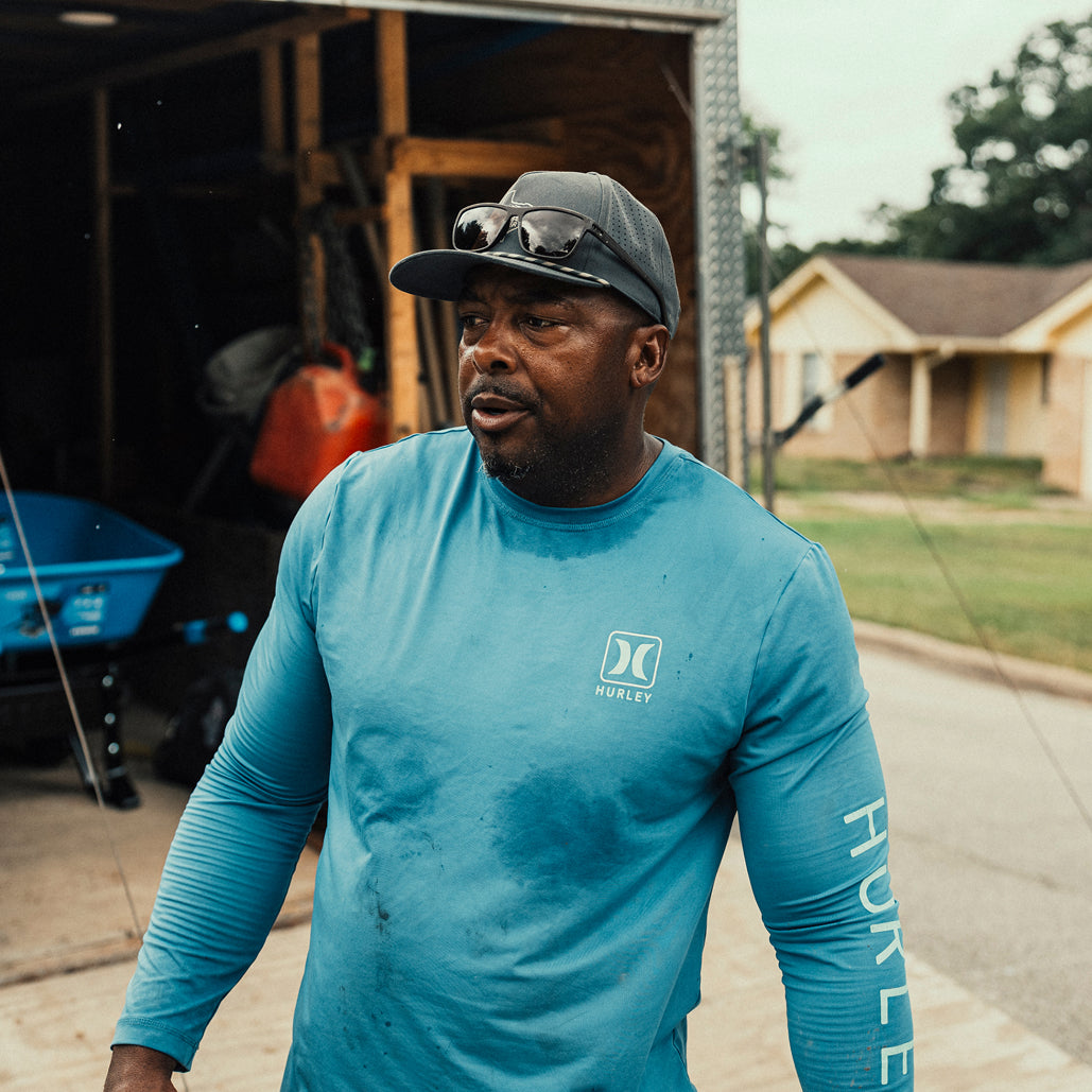 Construction worker standing beside an equipment trailer at a residential jobsite.