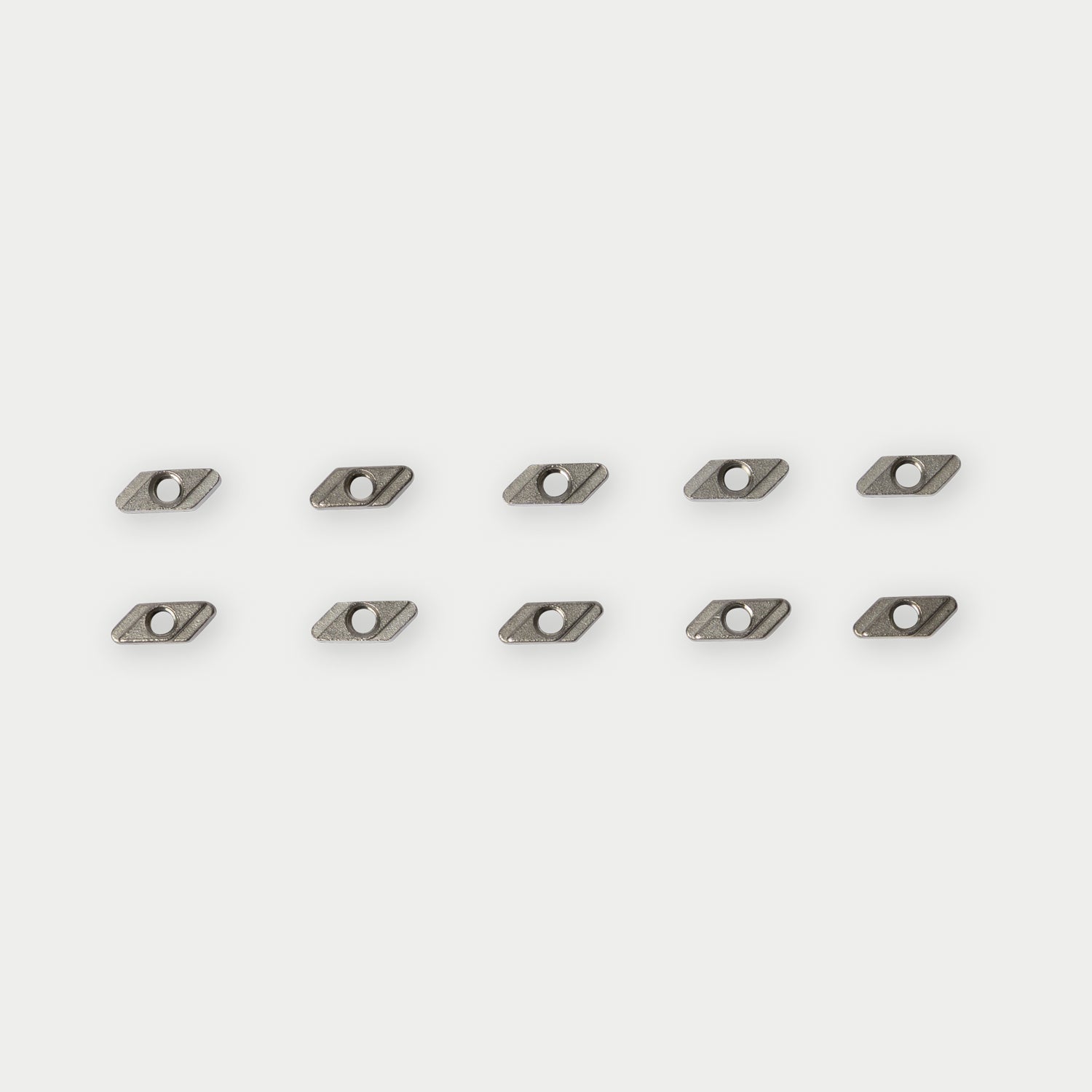 [C0011-NUT10-SIL] Ten small metallic rectangular tool inserts arranged in two rows of five on a light gray background.