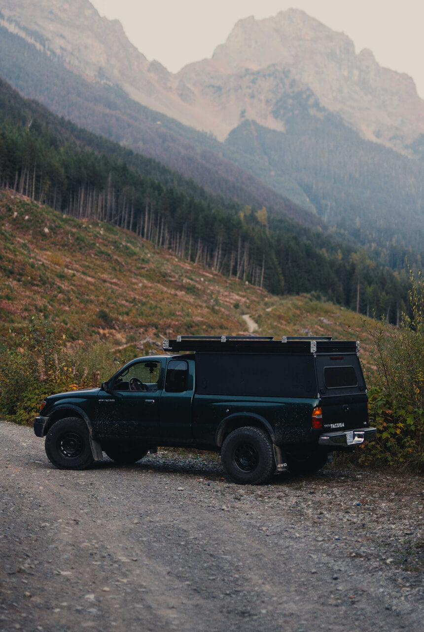 Black truck with a camper shell on a mountain road