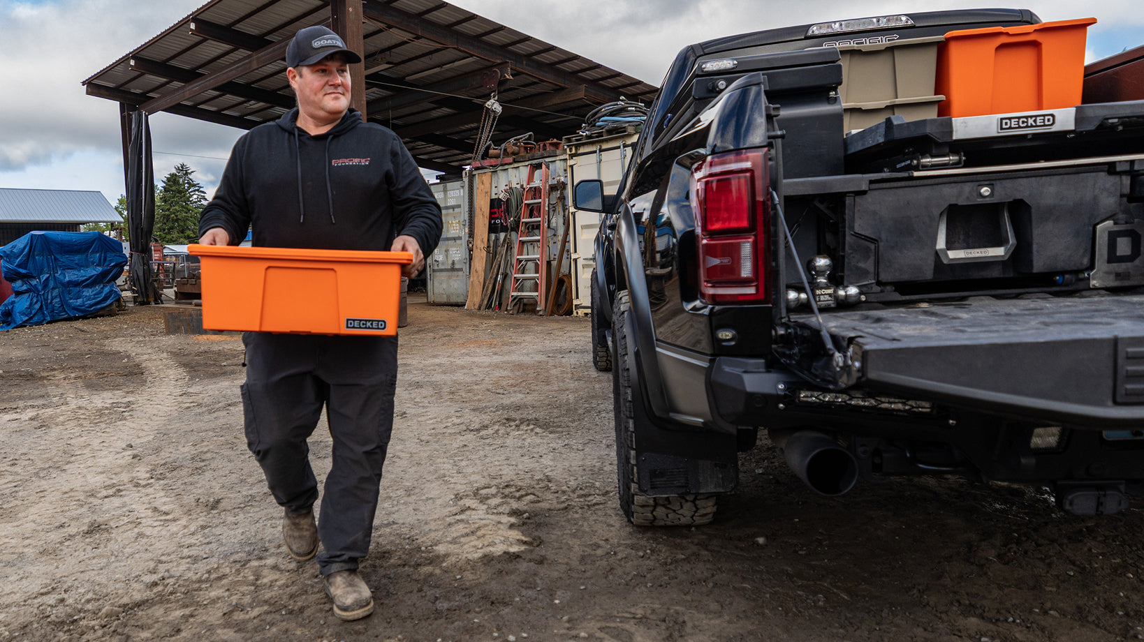 Concrete contractor carrying an orange DECKED payloader beside a pickup equipped with a Drawer System and CargoGlide.