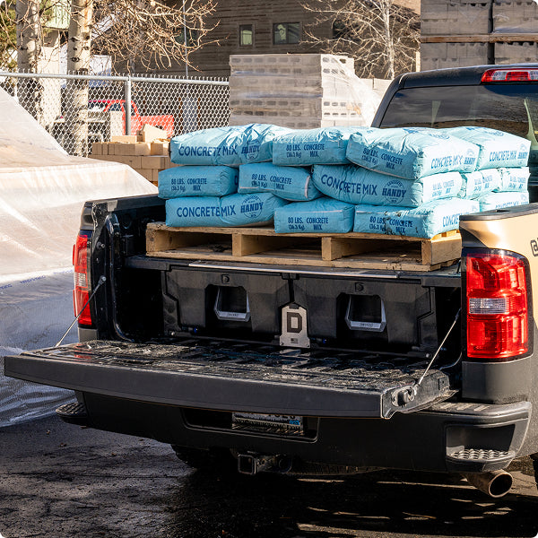 Bags of concrete mix loaded on top of a DECKED Drawer System in a pickup truck bed.