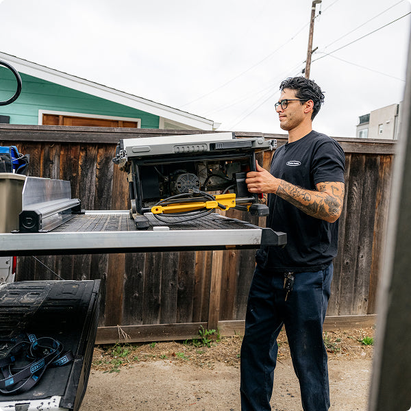 Contractor loading a table saw onto a Man loading heavy equipment DECKED CargoGlide in a pickup truck bed.