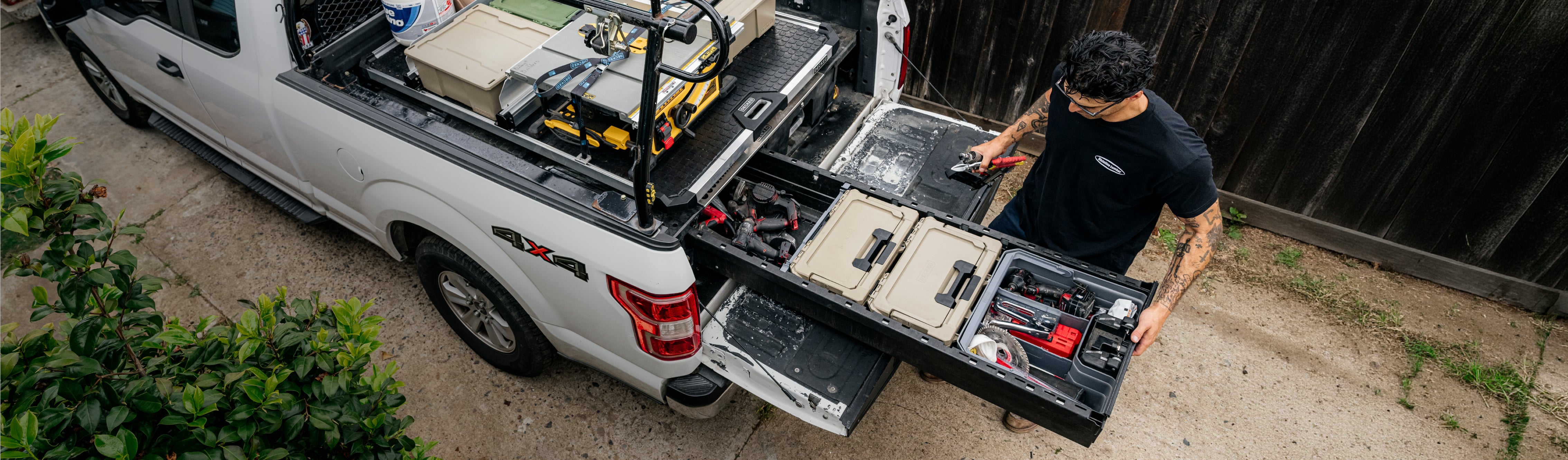 Contractor accessing organized tools and DECKED cases from open Drawer System drawers beneath a CargoGlide.
