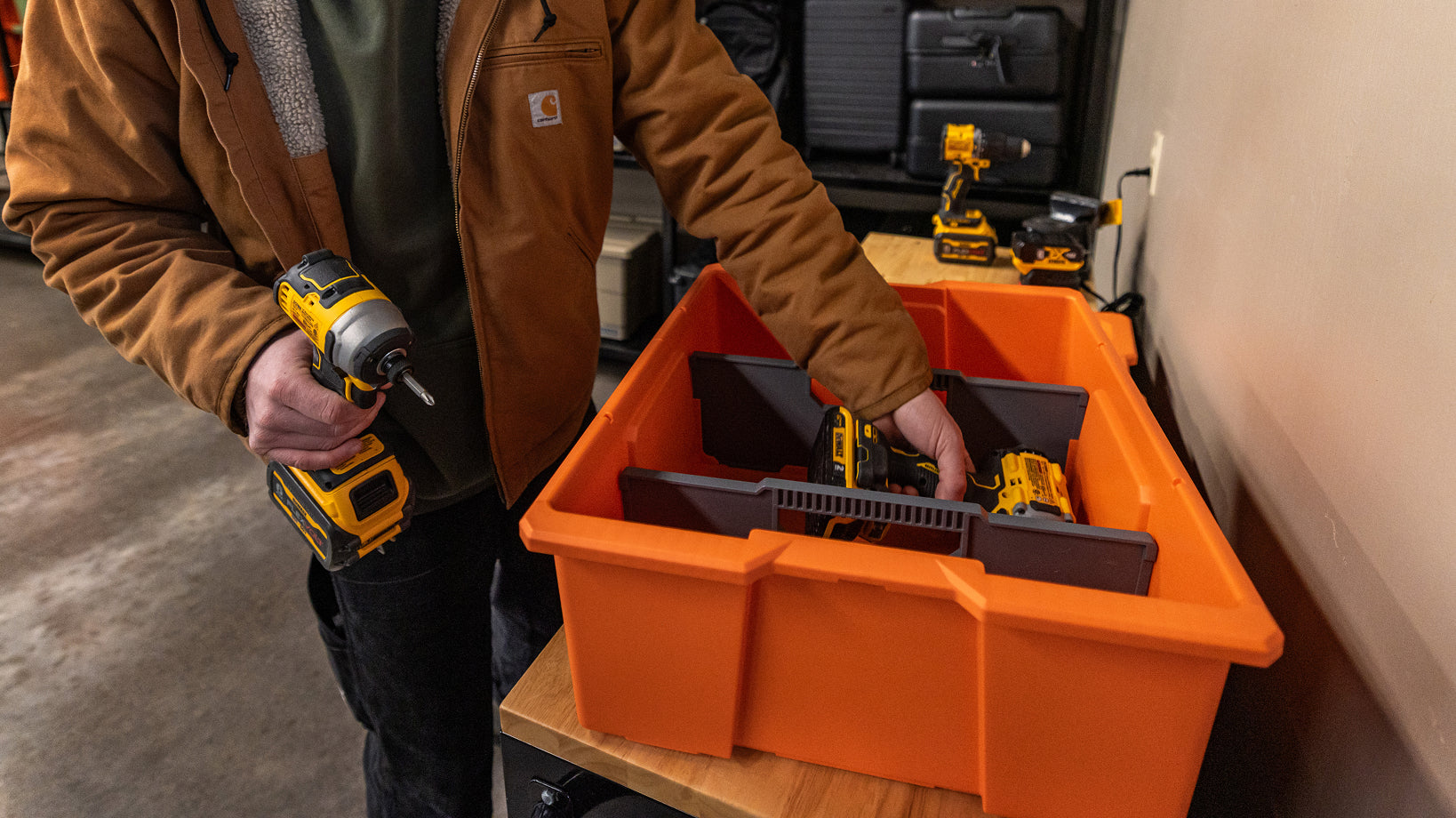 Worker organizing cordless drills in an orange DECKED D-co Case with dividers.