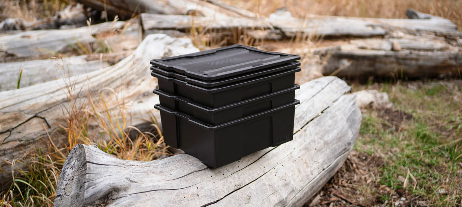 Black D-co bin sitting on a log in the backcountry
