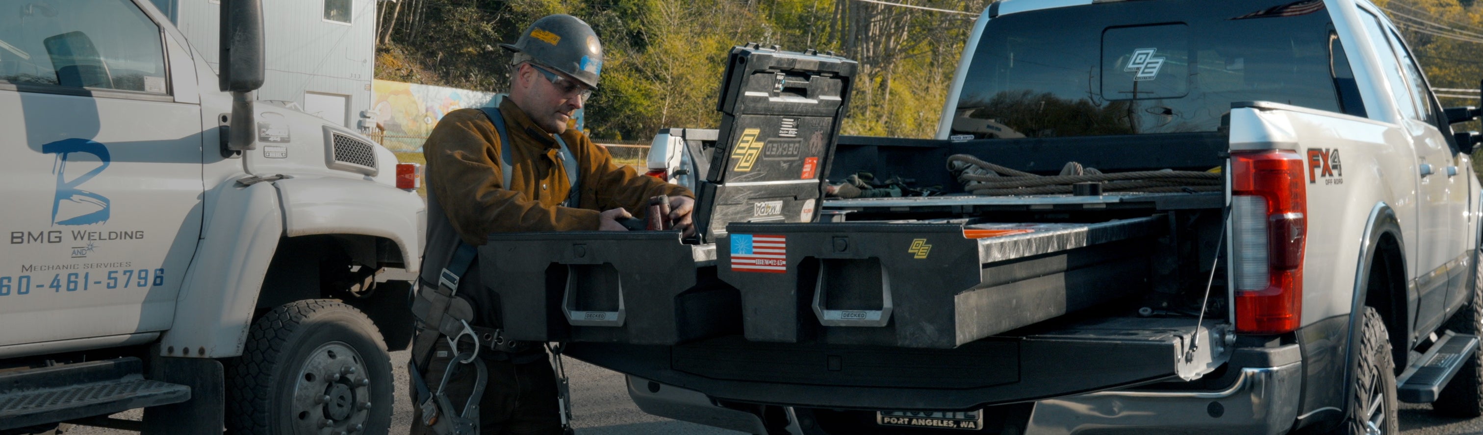 Welder accessing tools from open DECKED Drawer System drawers in a pickup truck bed.
