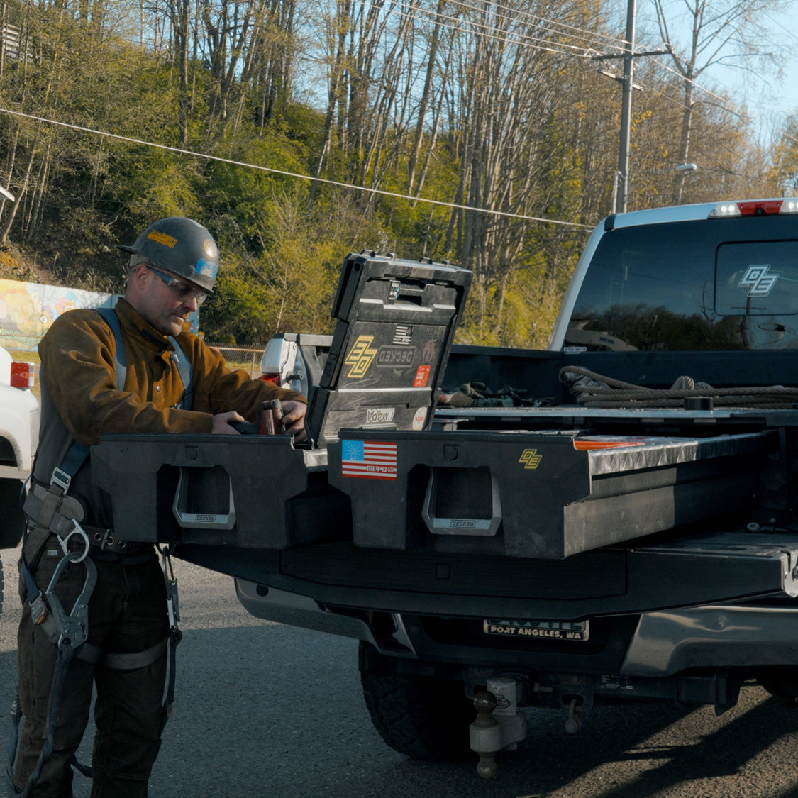 Welder accessing tools from open DECKED Drawer System drawers in a pickup truck bed.