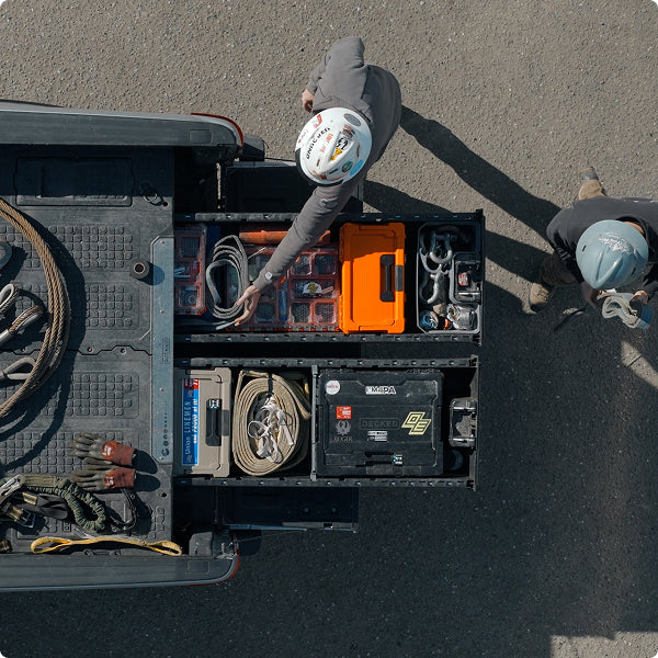 Overhead view of workers accessing organized rigging equipment and DECKED cases from open Drawer System drawers.