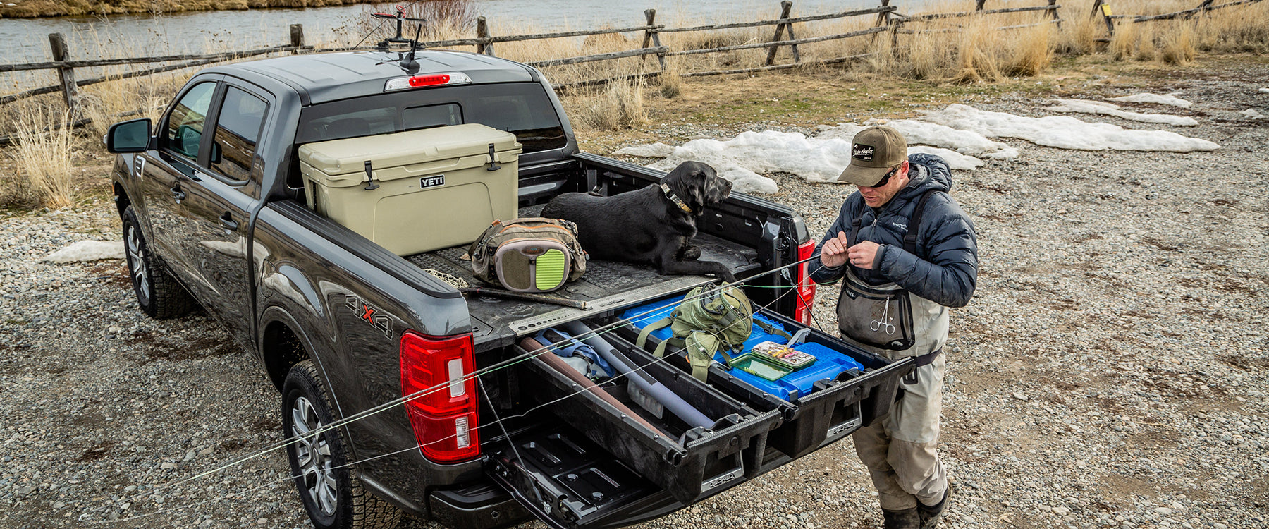 back of truck with a decked drawer system and a person going fly fishing