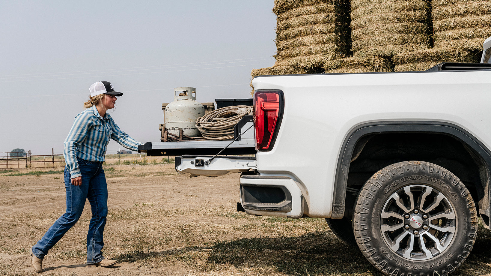 Rancher extending a DECKED CargoGlide loaded with a propane tank, rope, and equipment.