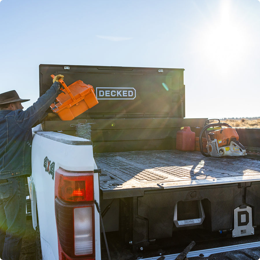 Rancher placing an orange DECKED D-co Case into a Tool Box above a Drawer System.