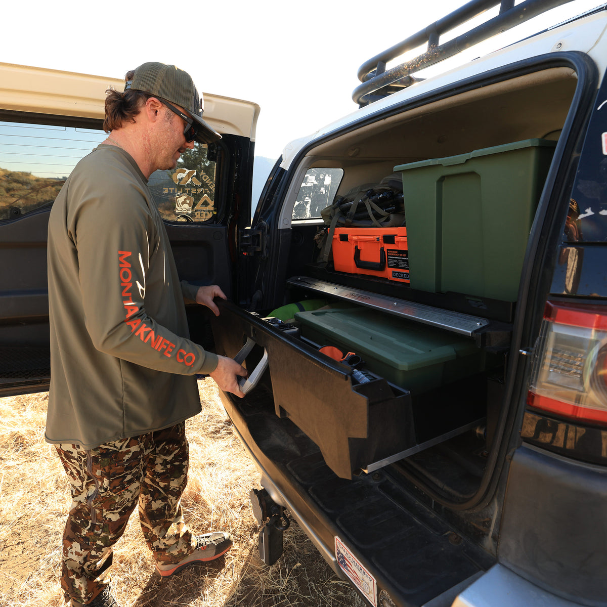 Man opening a DECKED Drawer System loaded with gear in the back of a Toyota FJ Cruiser.