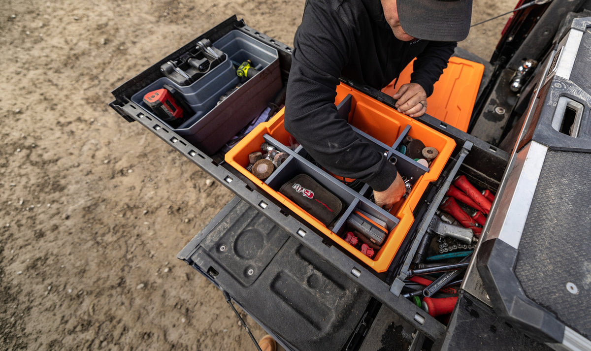 Image of man reaching in orange DECKED Payloader 32 with POD system installed for organized tools and gear.