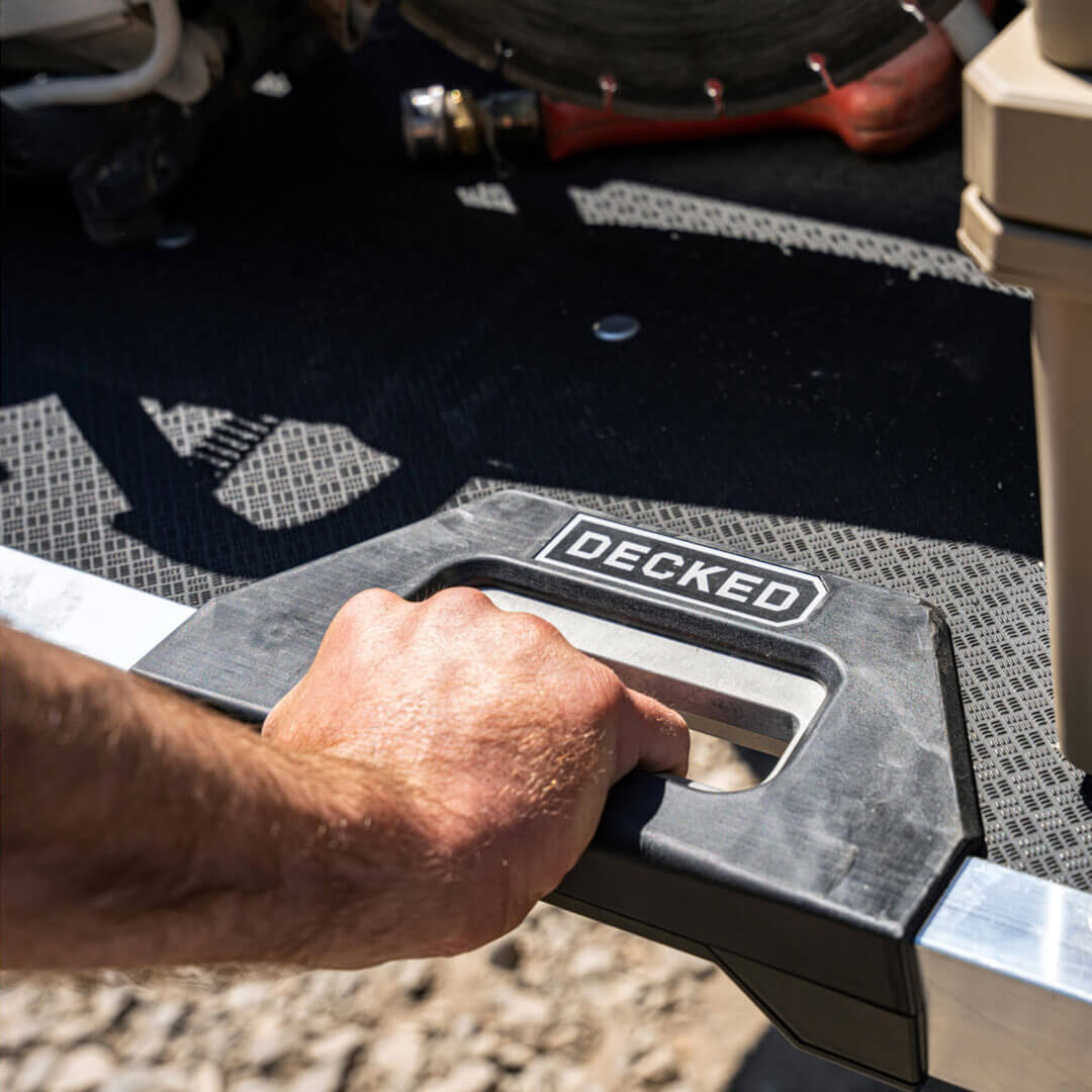 A man's hand pulling the CargoGlide's new grip-release handle to extend the system from his truck bed.