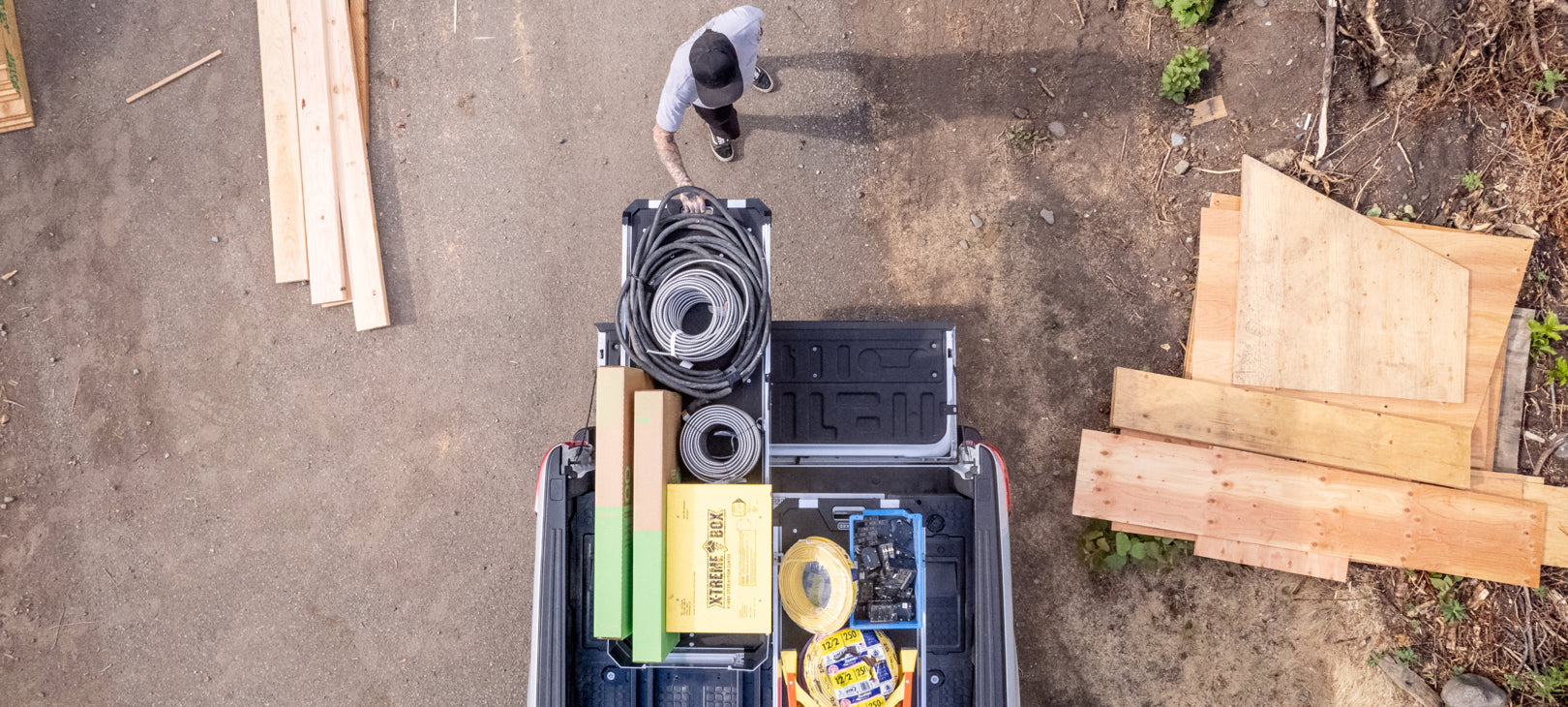 A bird's eye view of a man extending his CargoGlide 600 that is stacked with hoses and boxes from his truck bed.