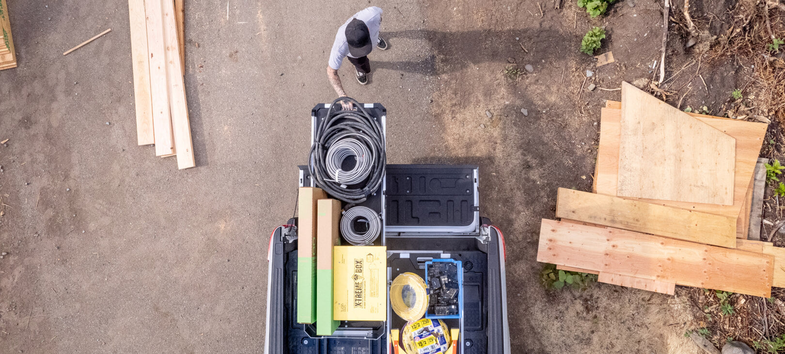 A bird's eye view of a man extending his CargoGlide 600 that is stacked with hoses and boxes from his truck bed.