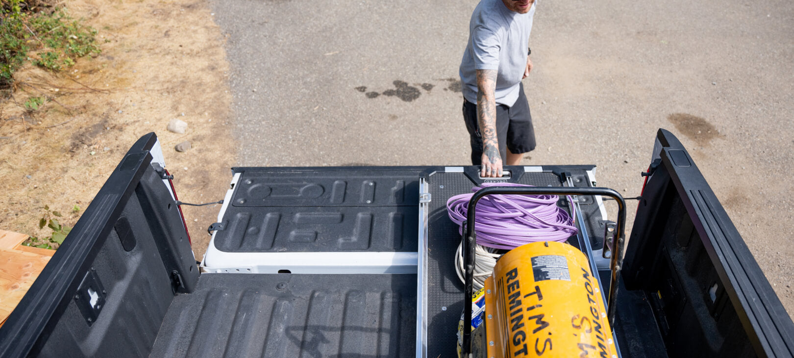 A man extending his CargoGlide 600 mounted in the left side of his midsize truck bed.