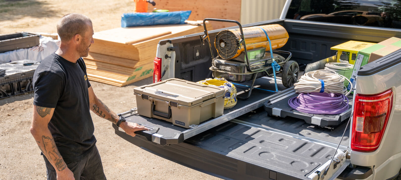 A man in a lumber yard extending his CargoGlide 600 loaded with tools and D-co Cases. His full-size truck has two CargoGlide 600s mounted side-by-side so he can haul and manage even more gear.