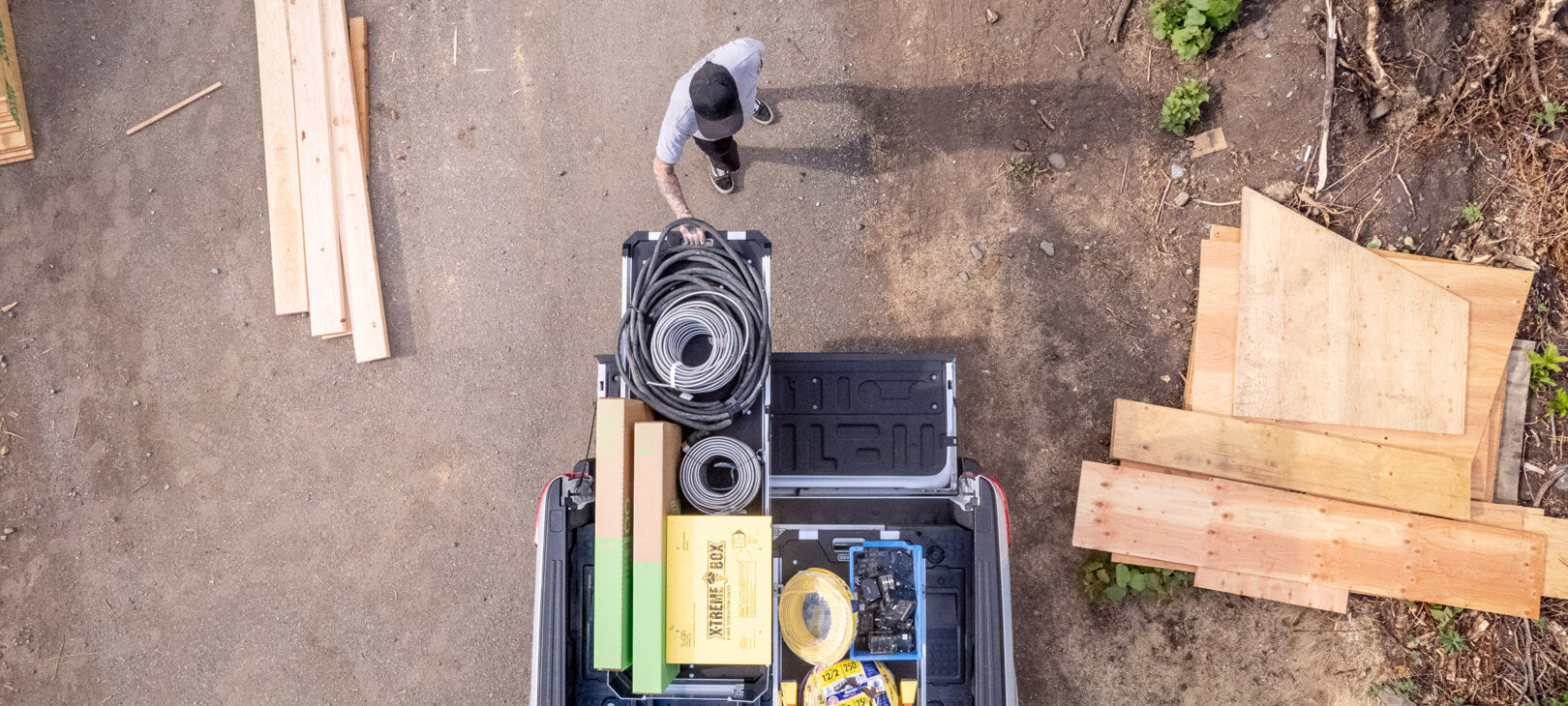 A bird's eye view of a man extending his CargoGlide 600 that is stacked with hoses and boxes from his truck bed.