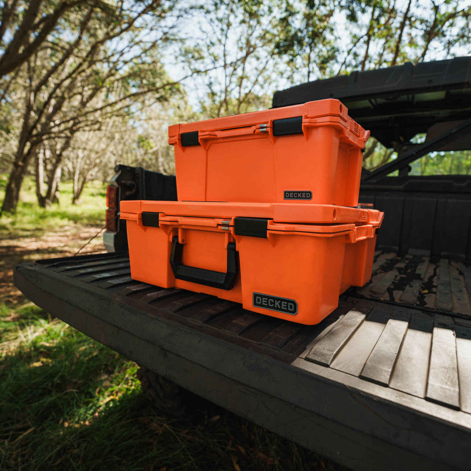 The Blaze Orange Sixer and Halfrack stacked on each other on the tailgate of a side-by-side.