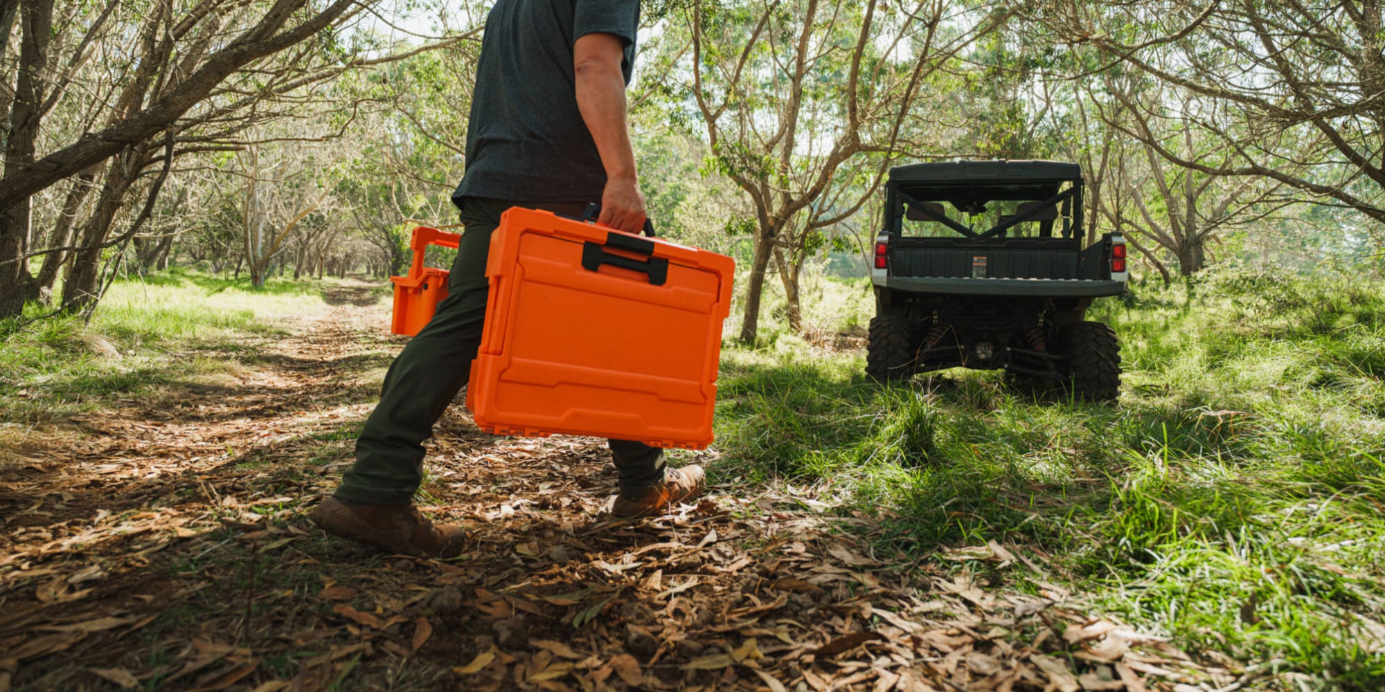 A man carrying his Blaze Orange Halfrack back to his side-by-side.