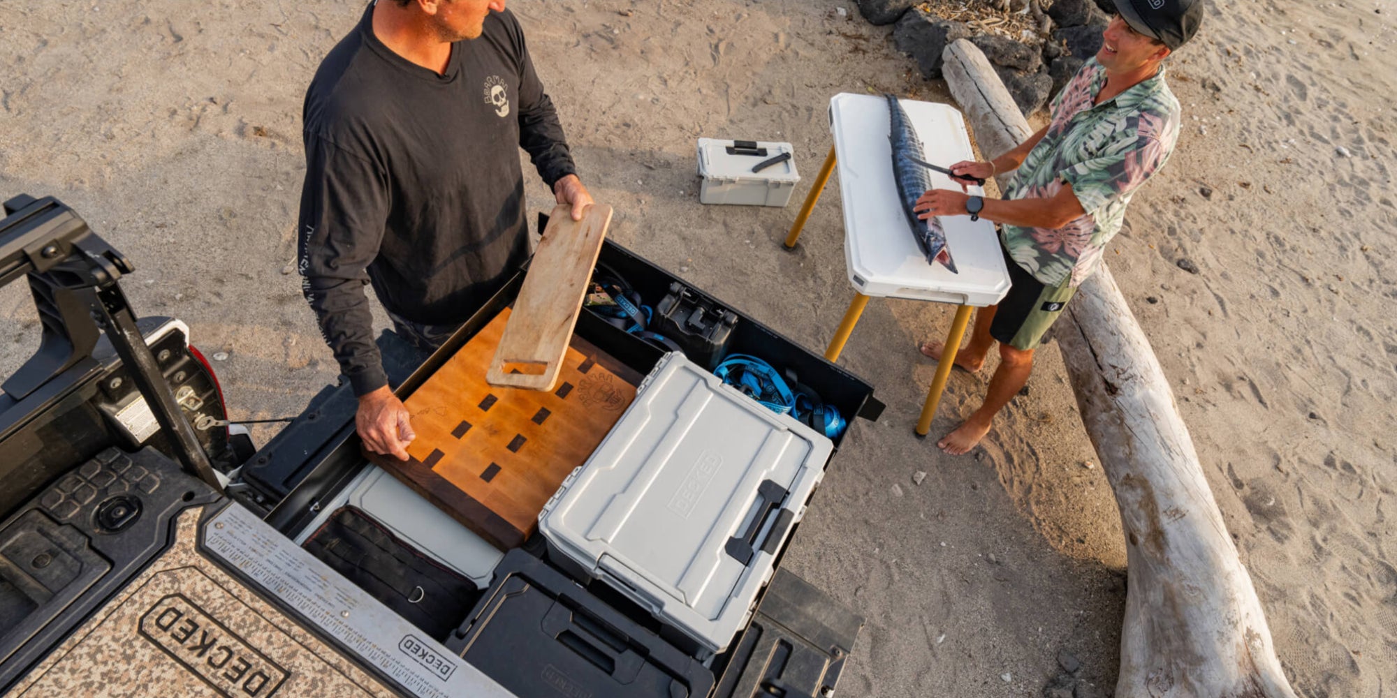 To friends filleting the catch of the day on their DECKED Drawer. The Cool Gray Halfrack serves as the perfect platform for a camp kitchen.