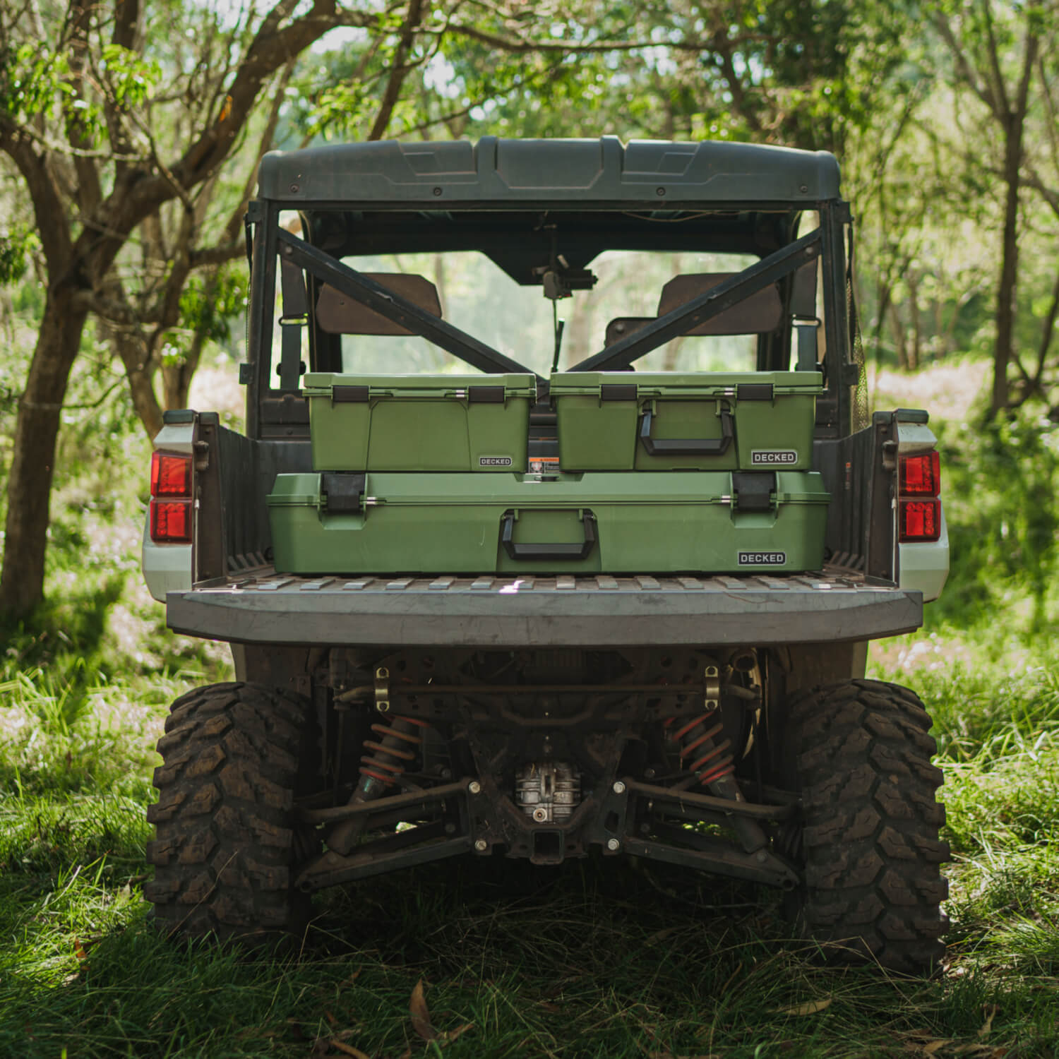 The family of Ranger Green D-co Cases, including the Sixer, Halfrack, and Honcho, stacked in the bed of a side-by-side.