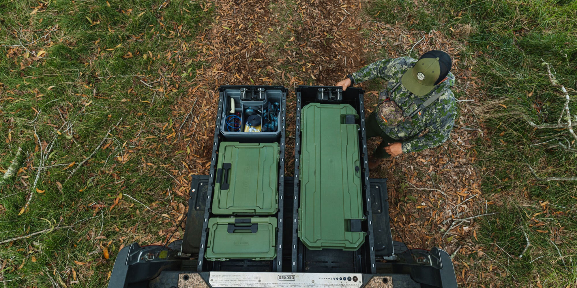 A man in camo admiring how organized his DECKED Drawer System is due to his collection of Ranger Green D-co Cases.