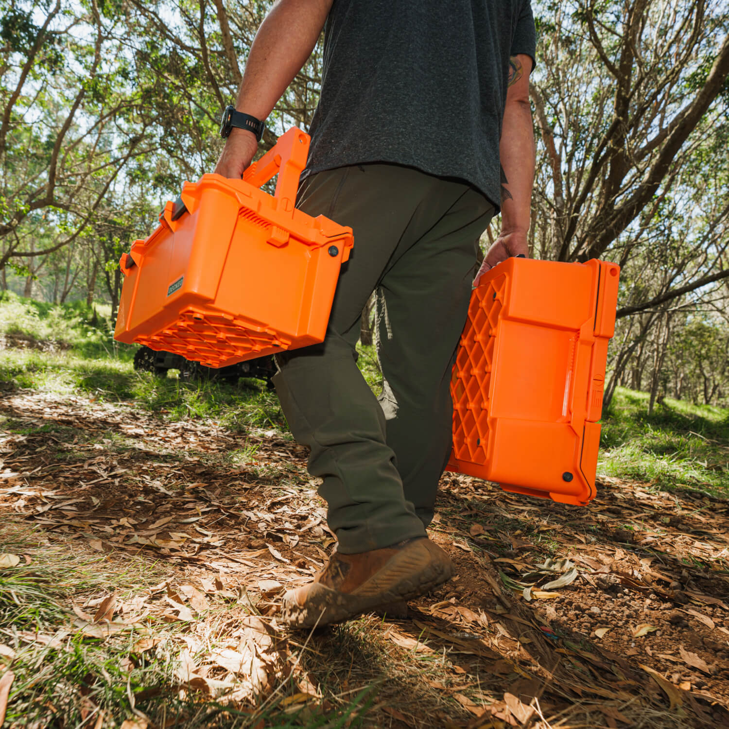 A man carrying the Blaze Orange Sixer and Halfrack D-co cases. The orange of the cases pops in the woods, making them easy to spot.