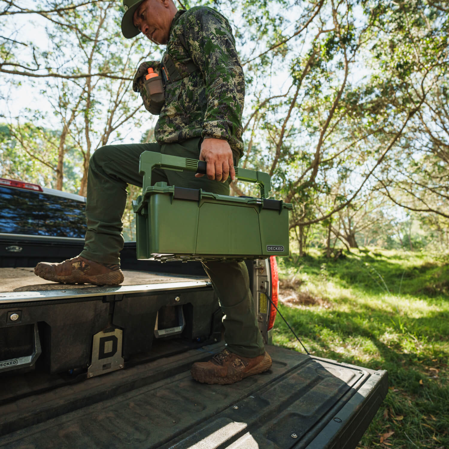 A hunter stepping up onto his DECKED Drawer System with his Ranger Green Sixer D-co Case in hand.