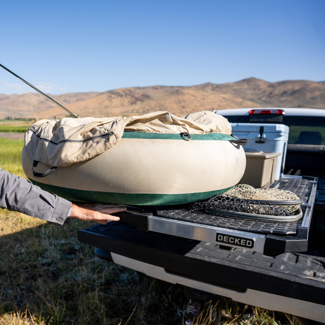 A CargoGlide with Battle Mat piled high with fishing gear being pulled out of a truck bed by a fisherman.