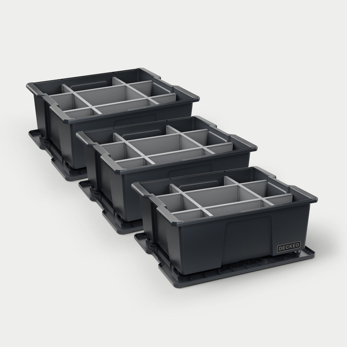 Three black DECKED Payloader bins with grey POD divider systems installed in all of them on a white background.
