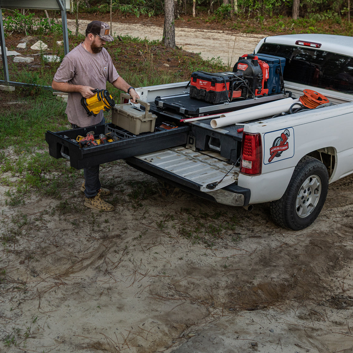 Plumber accessing organized power tools and a DECKED D-co Case from a Drawer System beneath a CargoGlide.