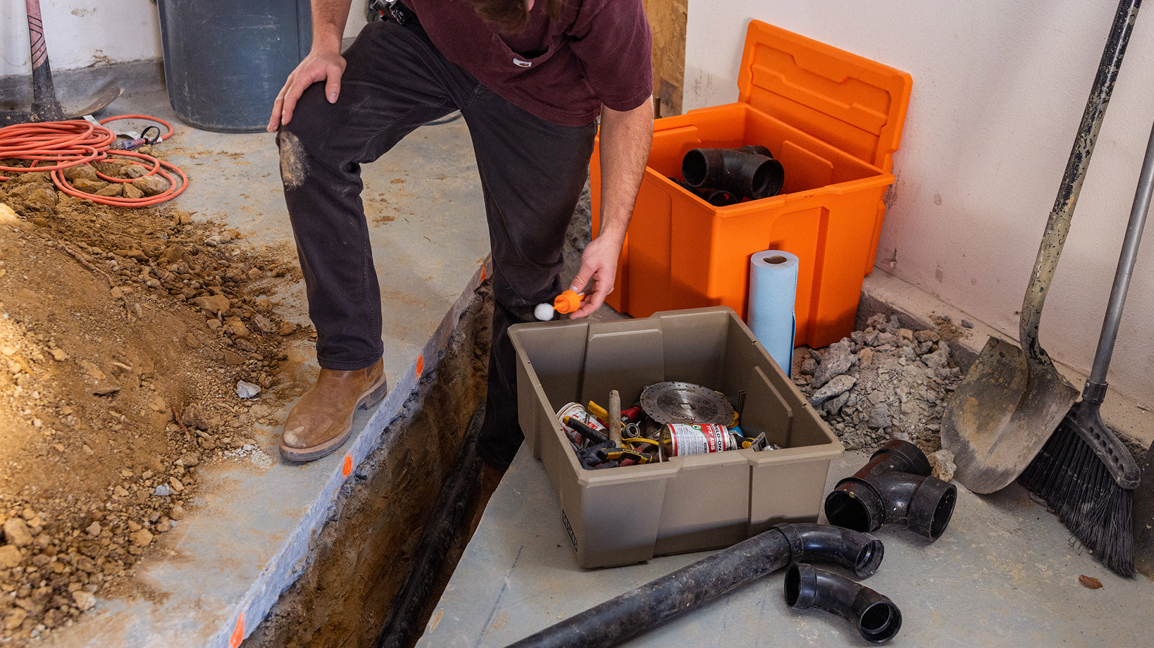 Plumber accessing fittings and supplies from DECKED payloaders beside an open trench.