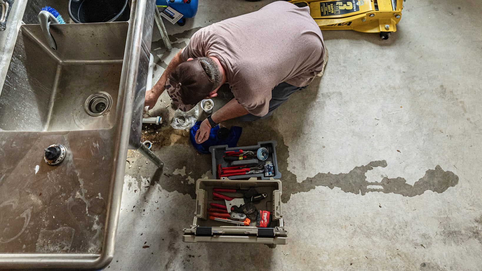 Plumber repairing a sink with hand tools organized in an open DECKED sixer.