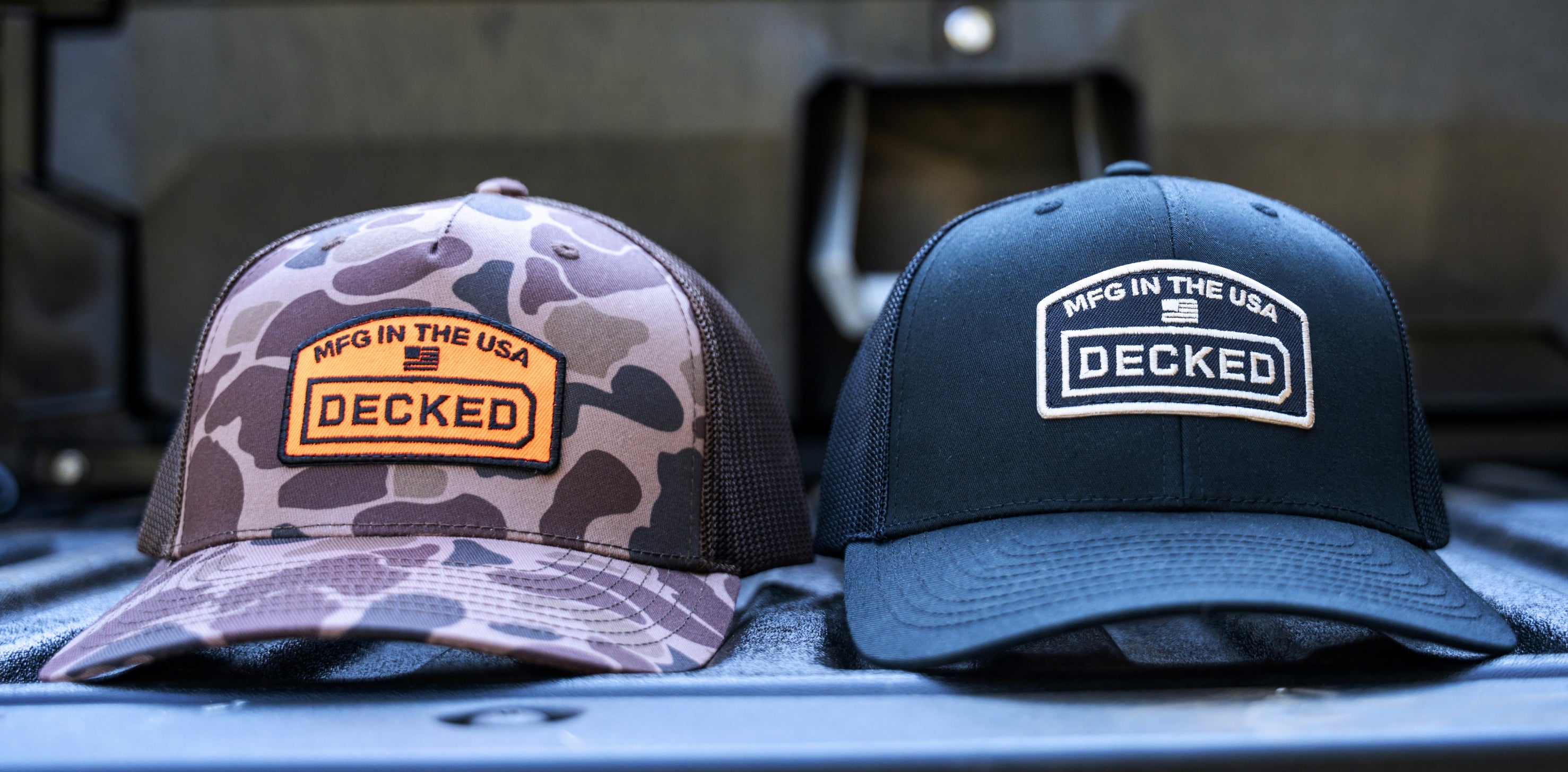 Both the black and camo DECKED hats sitting side by side on a truck's tailgate with a DECKED Drawer System in the background.